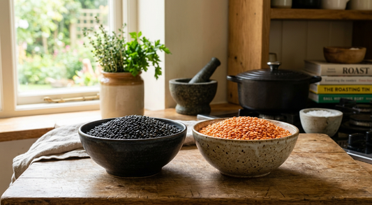 Black Sicilian lentils alongside red split lentils in two bowls on a wooden surface — UK home cook's variety comparison guide 2026